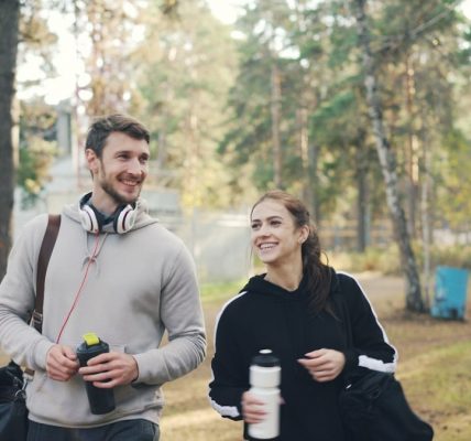 Couple walking outdoors with gym bags and water bottles