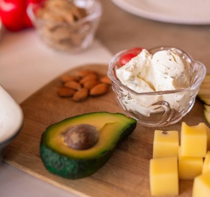 A vibrant platter of cheese, fruits, and vegetables on a wooden board, perfect for gatherings.